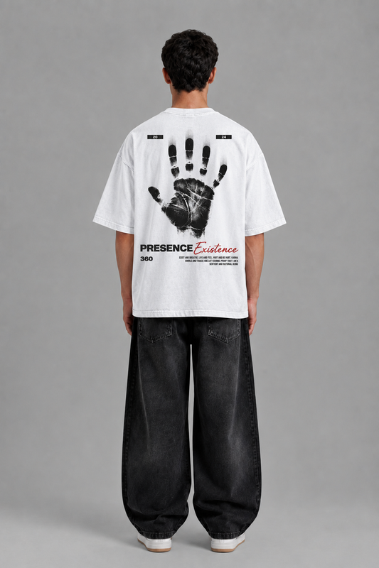 A man viewed from behind wearing a white t-shirt with a large black handprint graphic and text on the back, paired with loose black jeans, against a solid gray studio background.