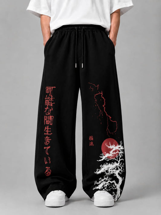 Black wide-leg sweatpants with red Japanese text and red/white graphic prints, shown on a model wearing a white t-shirt and white sneakers against a gray studio background.