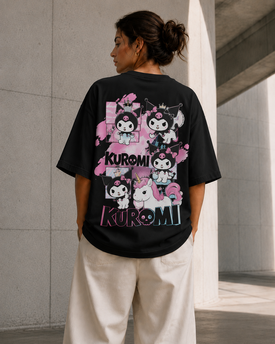 A woman wearing a black oversized T-shirt with a large Kuromi graphic print on the back, paired with off-white wide-leg pants, standing in a modern concrete corridor.