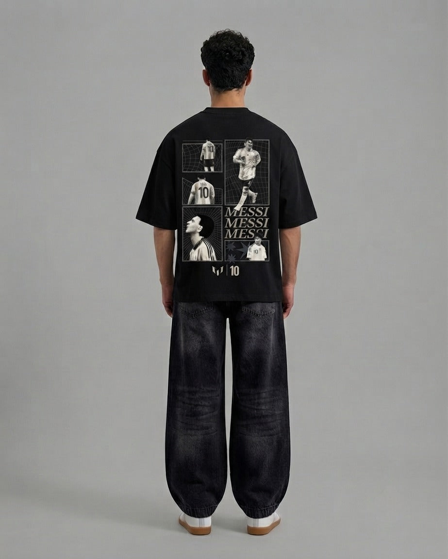 A model viewed from the back wearing a black t-shirt with a large white and gray Messi graphic print on the back, paired with dark wide-leg jeans, against a solid gray studio background.
