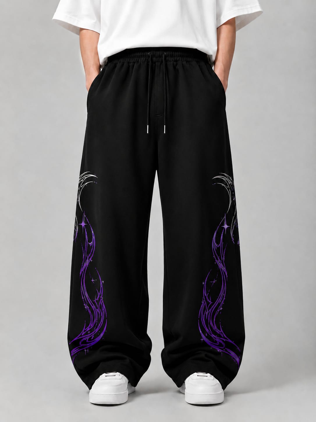 Black wide-leg sweatpants with purple flame-like graphic prints on the lower legs, shown on a model wearing a white t-shirt and white sneakers against a gray studio background.