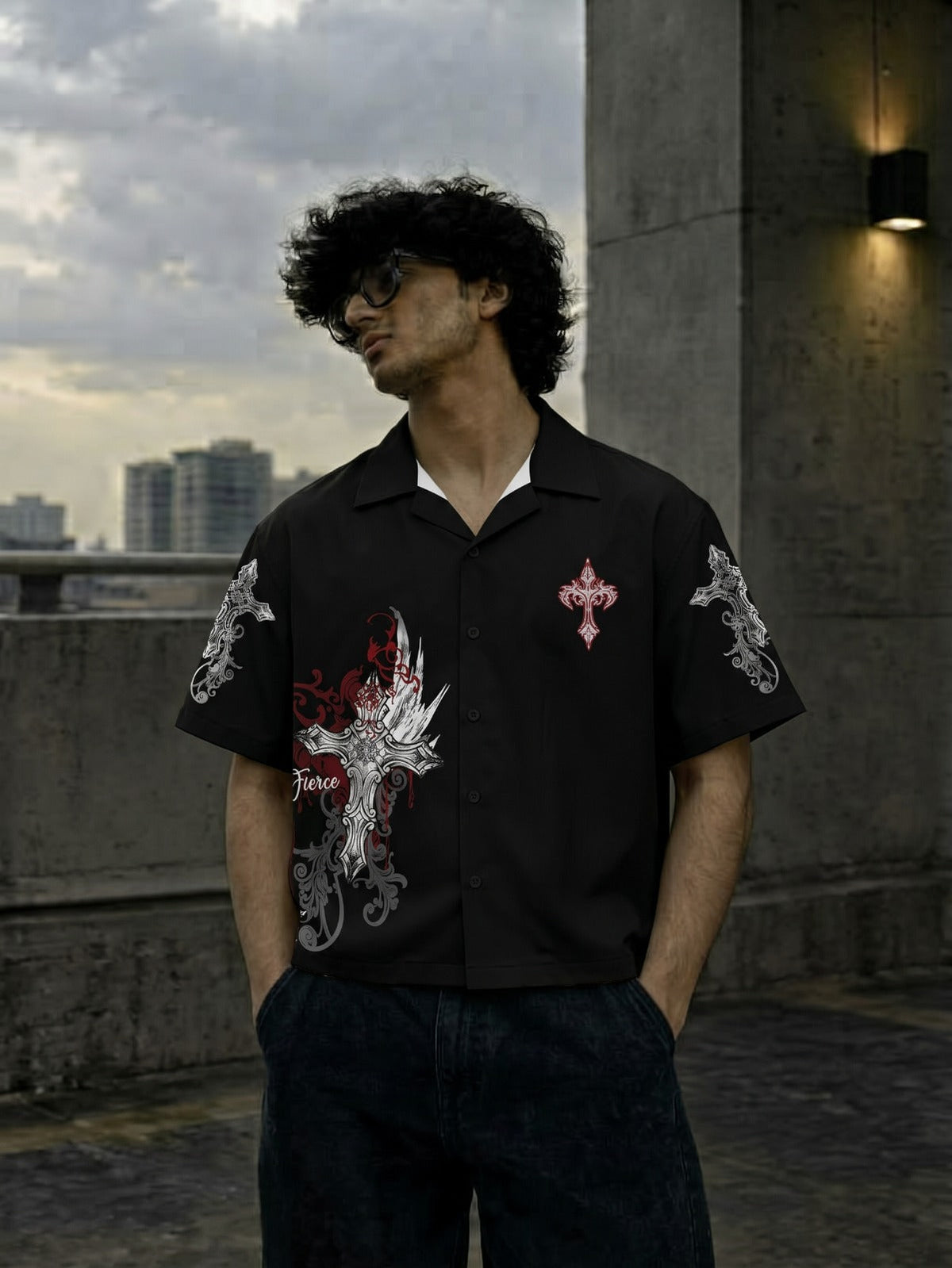 A man wearing a black short-sleeve button-up shirt with a red and silver dragon graphic on the front and a red cross emblem on the chest, standing on a concrete rooftop.