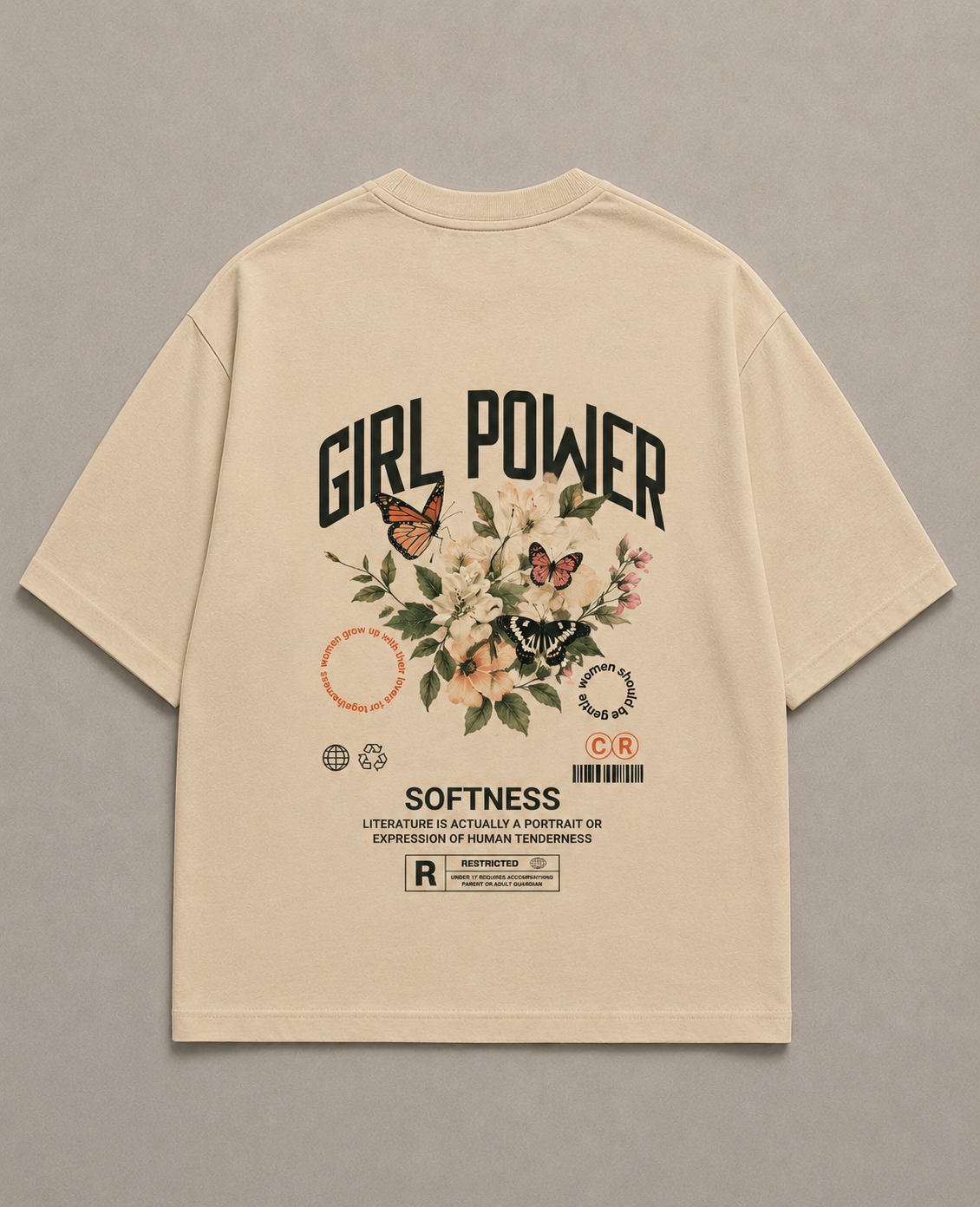 A beige short-sleeve t-shirt shown flat against a neutral gray background, featuring a large graphic print on the back with the words 'GIRL POWER' and 'SOFTNESS' and a floral/butterfly design.